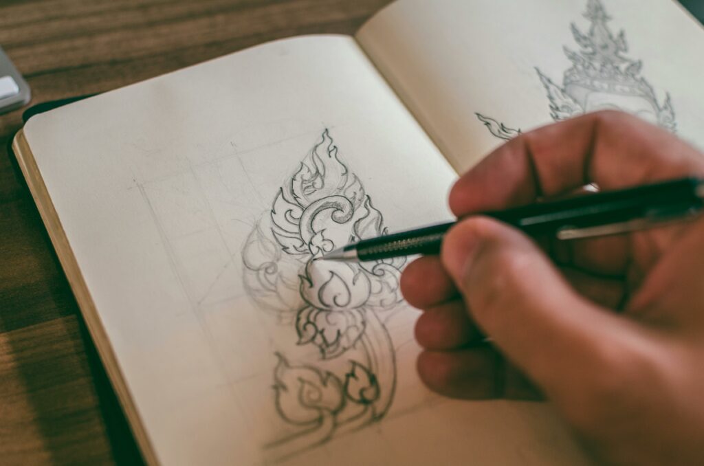 main en train de dessiner au crayon sur un carnet