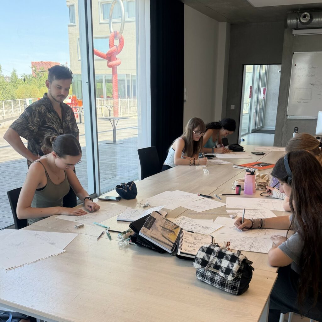 Participants du stage d'été Pivaut en atelier de dessin, accompagnés par un enseignant lors d'un exercice de perspective et de narration graphique.