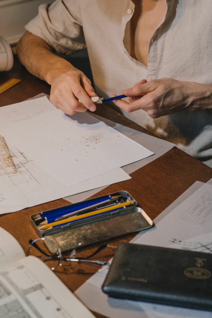 Étudiant taillant un crayon graphite au cutter avant de commencer un dessin d'observation sur une feuille de croquis.